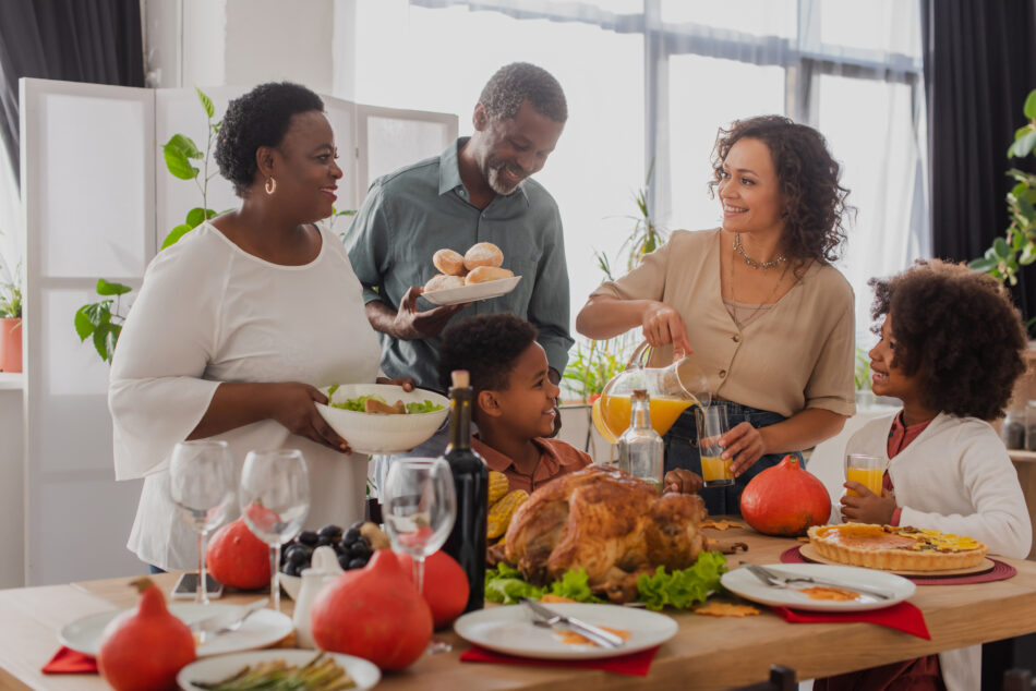 A family enjoying Thanksgiving dinner together in a clean, bright dining room with fresh food and natural light, representing the comfort and peace of mind that comes from using a professional deep cleaning service before the holidays.